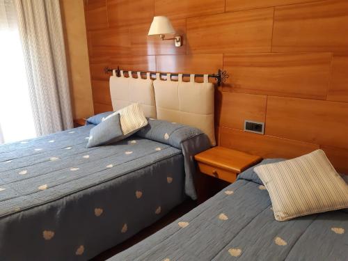 two beds in a room with wood paneling at Hostal La Placeta in Camprodon