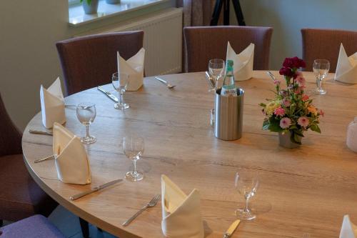 a long wooden table with a bottle of wine and flowers at Schlüter Hotel & Restaurant in Wankendorf