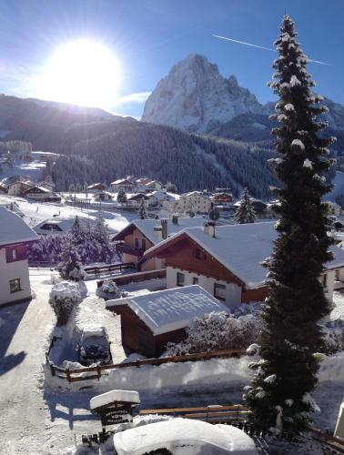 a snow covered village with a mountain in the background at Appartamenti Olympic in Santa Cristina in Val Gardena