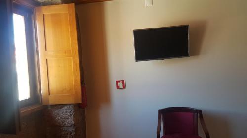a flat screen tv on a wall next to a door at Olhares do Douro "A casa do Avô Zé" in Torre de Moncorvo