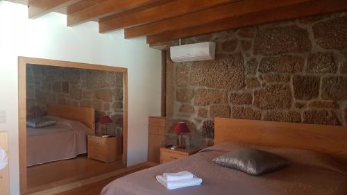 a bedroom with two beds and a stone wall at Olhares do Douro "A casa do Avô Zé" in Foz do Sabor