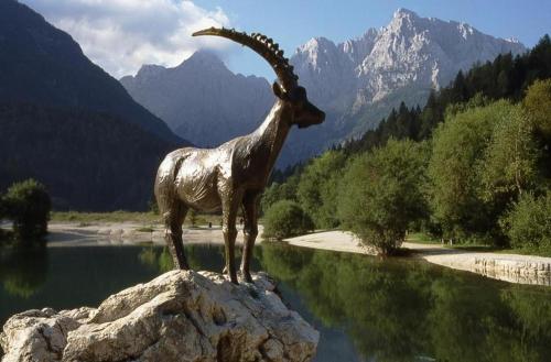 a statue of a goat standing on a rock near water at Vila Mojca Apartma Eva-Neža, Kranjska Gora (center) in Kranjska Gora