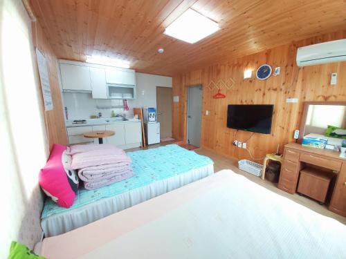 a small room with a bed and a kitchen at Feeling Good House in Jeju