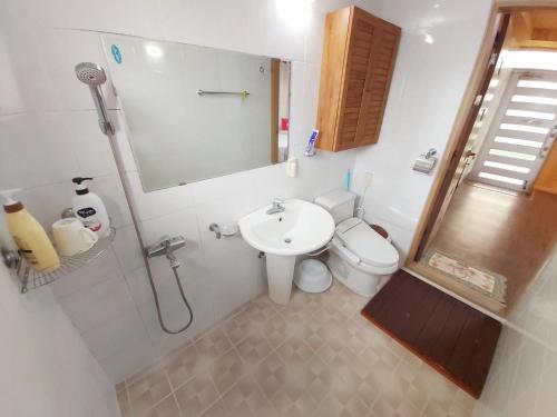 a bathroom with a sink and a toilet and a mirror at Feeling Good House in Jeju