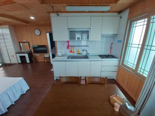 a kitchen with white cabinets and a sink and two chairs at Feeling Good House in Jeju