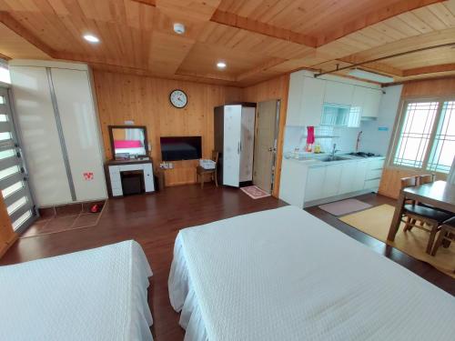 a large room with two beds and a kitchen at Feeling Good House in Jeju