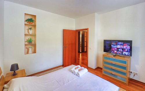 a bedroom with a bed and a dresser and a television at Predeal Fine Apartaments Clabucet in Predeal