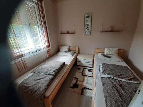 2 camas en una habitación pequeña con ventana en Pálma Vendégház, en Zalakaros