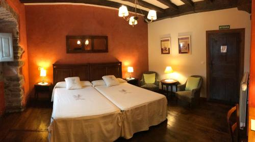 a bedroom with a bed and chairs in a room at Casa Rural Zigako Etxezuria in Ziga