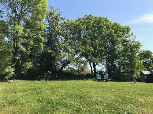 two benches and a picnic table in a field with trees at Glatigny Farmhouse - close to beach - proche de la plage in Glatigny