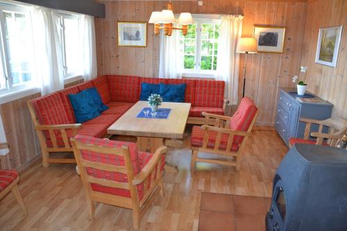 ein Wohnzimmer mit einem roten Sofa, einem Tisch und Stühlen in der Unterkunft Ørterstølen Hytter in Gol