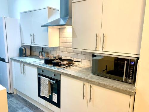 a kitchen with white cabinets and a microwave at Victory hot tub house in Blackpool