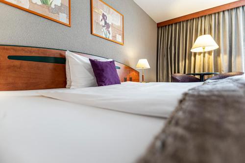 a hotel room with a large bed with purple pillows at Hotel Münchwilen in Wil