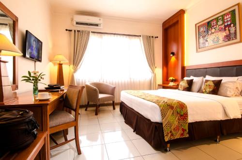 ein Hotelzimmer mit einem Bett, einem Schreibtisch und einem Fenster in der Unterkunft Griya Sentana Hotel in Yogyakarta