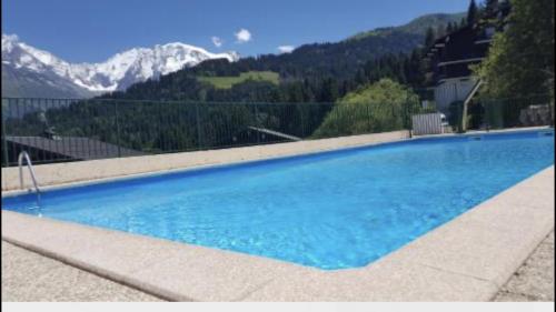 Studio Turquoise quartier Grattague vue MontBlanc في سان جيرفيه ليه بان: مسبح ازرق كبير مع جبال في الخلفية