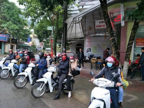 a group of people riding motorcycles down a street at Ngan Ha Homestay in Ha Giang