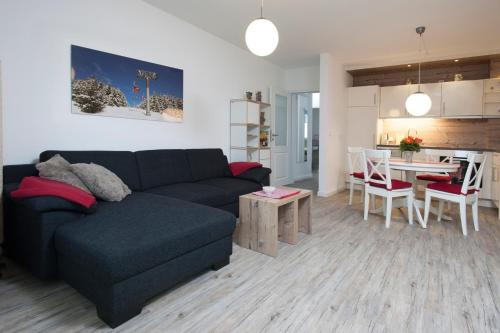 un soggiorno con un divano nero e una cucina di Apartment an der Wurmbergseilbahn 1 a Braunlage