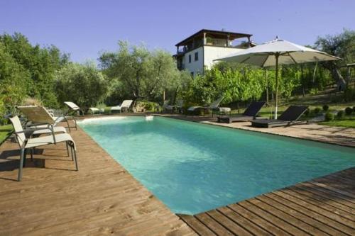 a swimming pool with chairs and an umbrella at Il Fiorile in Vitorchiano