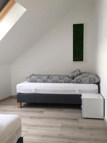 uma cama num quarto com uma parede branca em Jókai Apartman em Dunaföldvár