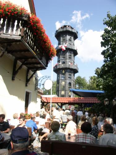 a crowd of people sitting outside of a building with a tower at Turmgaststätte Löbau in Löbau