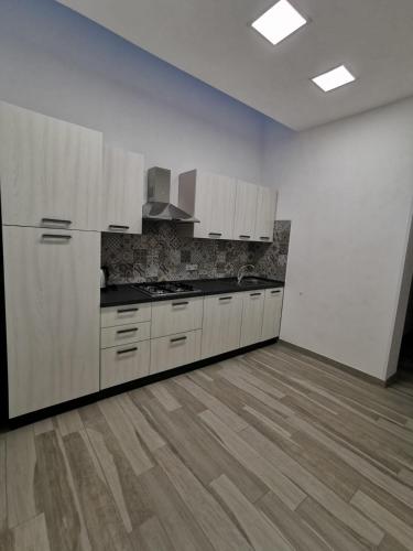 a kitchen with white cabinets and a wooden floor at B&B La Casa di Pino in Lampedusa