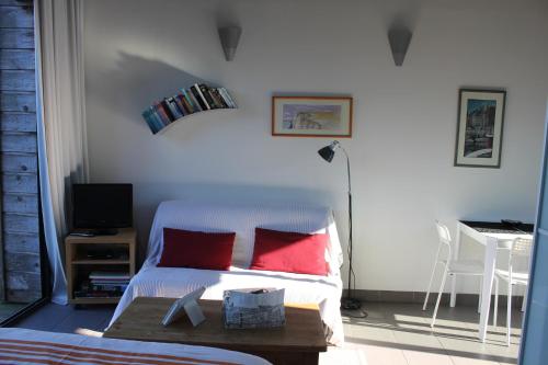 een slaapkamer met een bed met rode kussens en een tafel bij Le petit Zeph in Varengeville-sur-Mer