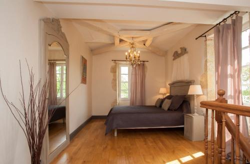 a bedroom with a bed and a chandelier at Maison d'hôtes de Charme Les Bruhasses in Condom