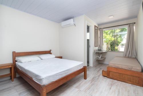 1 dormitorio con cama y ventana en CASA FRANK COM PISCINA EM MARISCAL, en Bombinhas