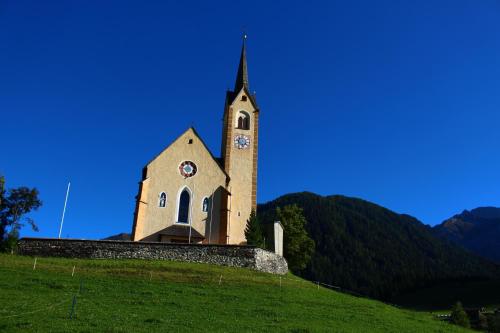 a church sitting on top of a grassy hill at Ferienhaus Köck in Kartitsch