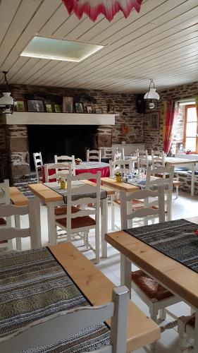 una sala da pranzo con tavoli in legno e sedie bianche di Auberge de Keringar a Le Conquet