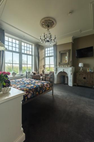 a large room with a bed and a fireplace at Pastorie Stella Marie in Oudeschild