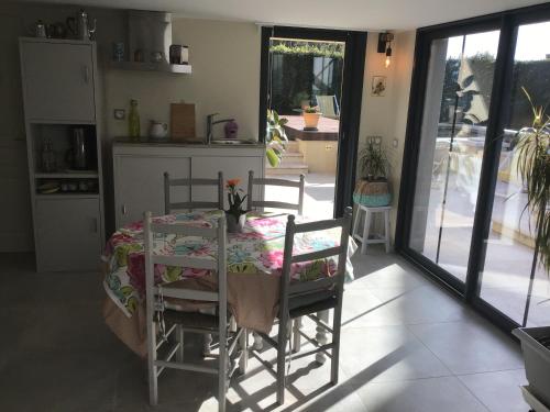 una cocina con mesa y sillas y una cocina con puertas correderas de cristal en Villa des marronniers en Laudun