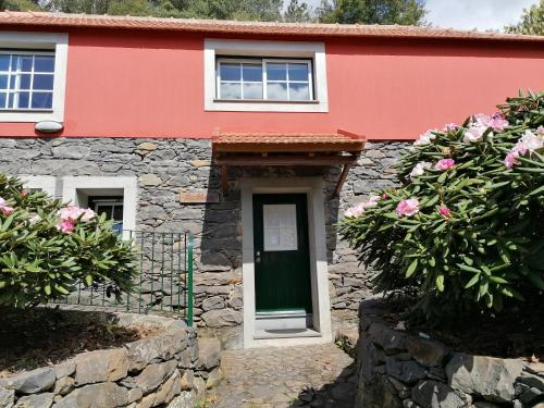 a red house with a green door and flowers at Casas de Pedra in Camacha
