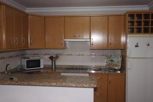 - une cuisine avec des placards en bois et un réfrigérateur blanc dans l'établissement Apartamento La Ubilla, à Famara