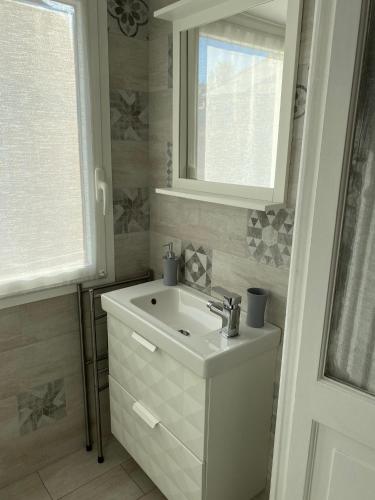 a white bathroom with a sink and a window at La Casetta di Dory sul Mare in Genova