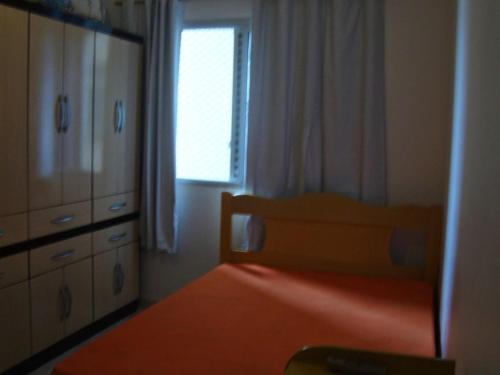 ein Schlafzimmer mit einem Bett, einer Kommode und einem Fenster in der Unterkunft APARTAMENTO EM SÃO VICENTE - SP in São Vicente