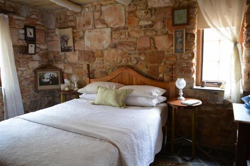 1 dormitorio con 1 cama grande en una pared de piedra en Trestrail Cottage Accommodation, en Clare