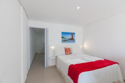 um quarto branco com uma cama branca com um cobertor vermelho em Pousada Pedras do Mariscal em Bombinhas