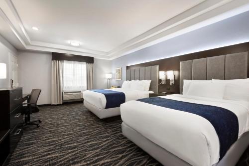 a hotel room with two beds and a desk at Days Inn & Suites by Wyndham Houston Hobby Airport in Houston