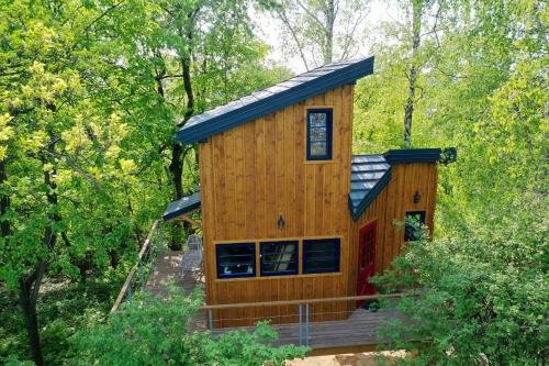 a large wooden cabin with a porch in the woods at Węgiełek Treehouse in Kazimierz Dolny