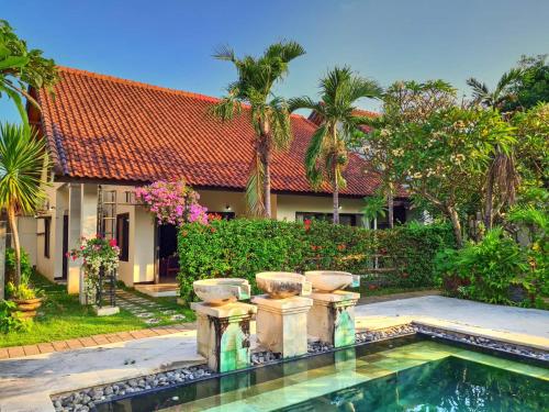 a house with a swimming pool in front of a yard at Sayang Taman Villas in Sanur