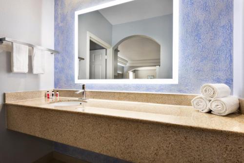 a bathroom with a sink and a mirror at Days Inn & Suites by Wyndham Houston Hobby Airport in Houston