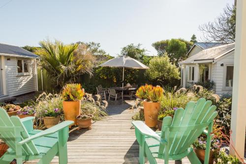 a wooden deck with chairs and an umbrella and plants at Elliott Street Gem in Nelson