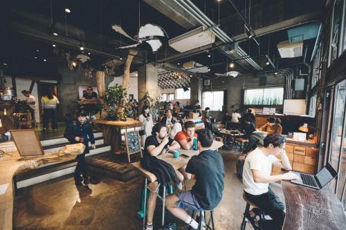 um grupo de pessoas sentadas em um restaurante com laptops em Nui. HOSTEL & BAR LOUNGE em Tóquio