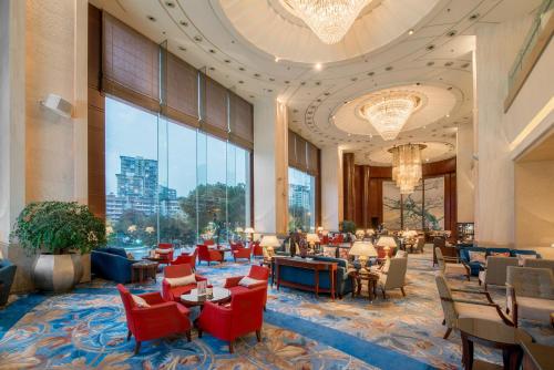 um átrio do hotel com mesas e cadeiras e uma grande janela em Shangri-La Chengdu em Chengdu