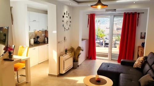 a living room with a couch and a kitchen with red curtains at Apartments Nancy in Kotor