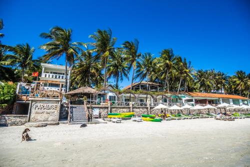 a beach with chairs and umbrellas and palm trees at Paradise Resort Doc Let - All Inclusive in Doc Let