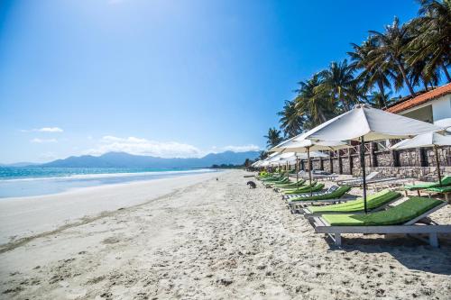 a row of beach chairs and umbrellas on a beach at Paradise Resort Doc Let - All Inclusive in Doc Let