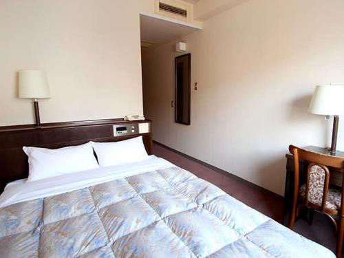 a bedroom with a large bed and a desk at Hotel Welcome Matsumoto in Matsumoto