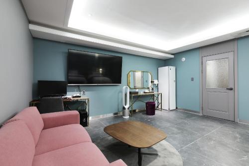 a living room with a pink couch and a flat screen tv at El Tower Hotel in Gunsan